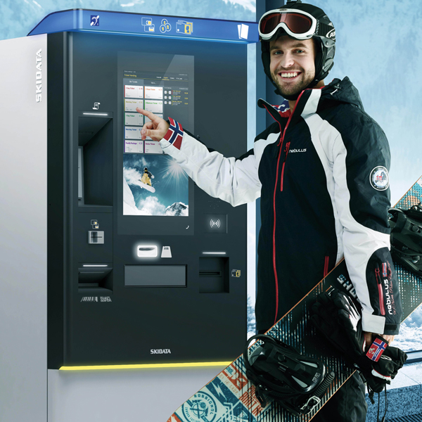 a man with snowboard gear in front of a ski pass vending machine